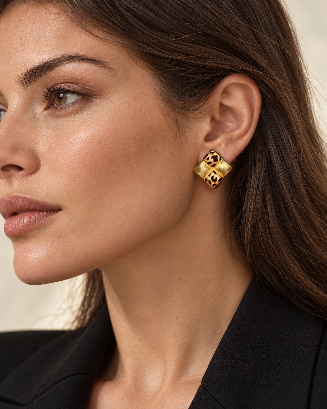 Square leopard checkerboard stud earring worn on an earlobe, showing alternating enamel and textured gold-tone tiles.