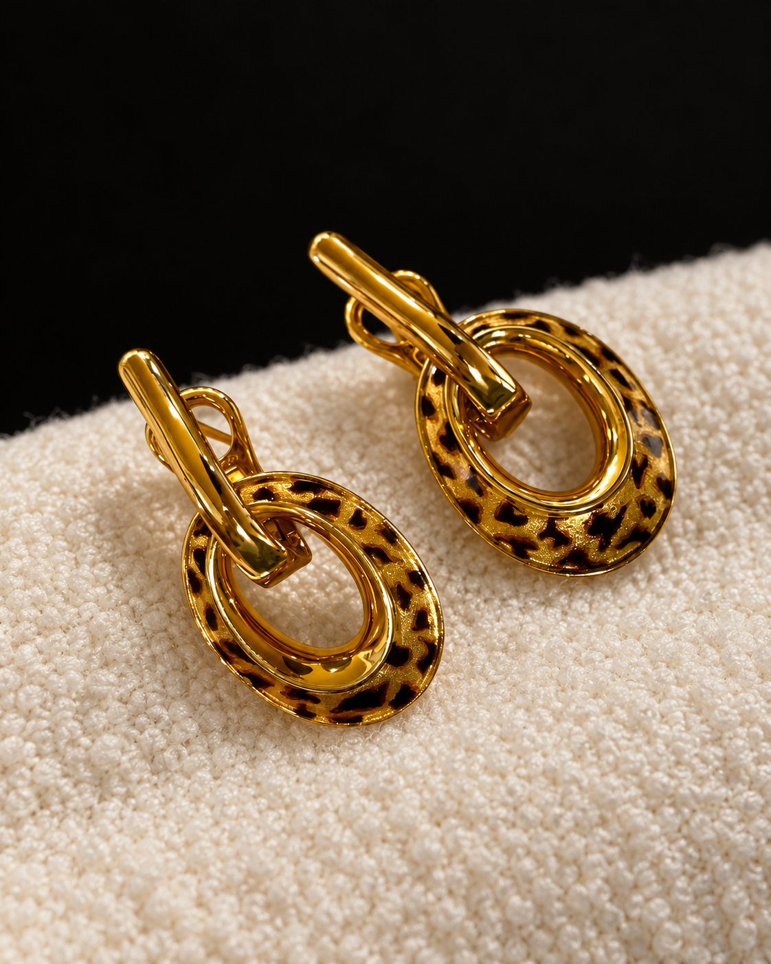 A pair of Theiaura Leopard Loop Hoop Earrings on ivory boucle fabric